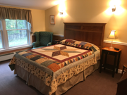 An upstairs room with a queen bed, cozy colors, and quilts. This room offers a bath with a five-foot walk-in shower.