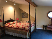 An upstairs corner room with a queen poster bed and a small couch tucked under the eaves. This spacious room offers a bath with a walk-in shower.